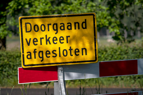 a yellow and red sign sitting on the side of a road